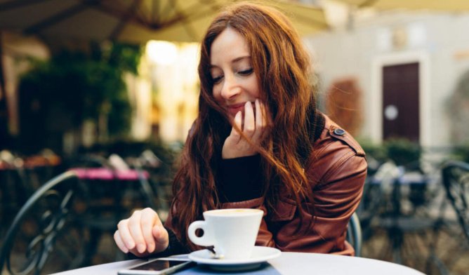 Illustrasjonsfoto: Dame på cafe med kaffekopp og mobiltelefon
