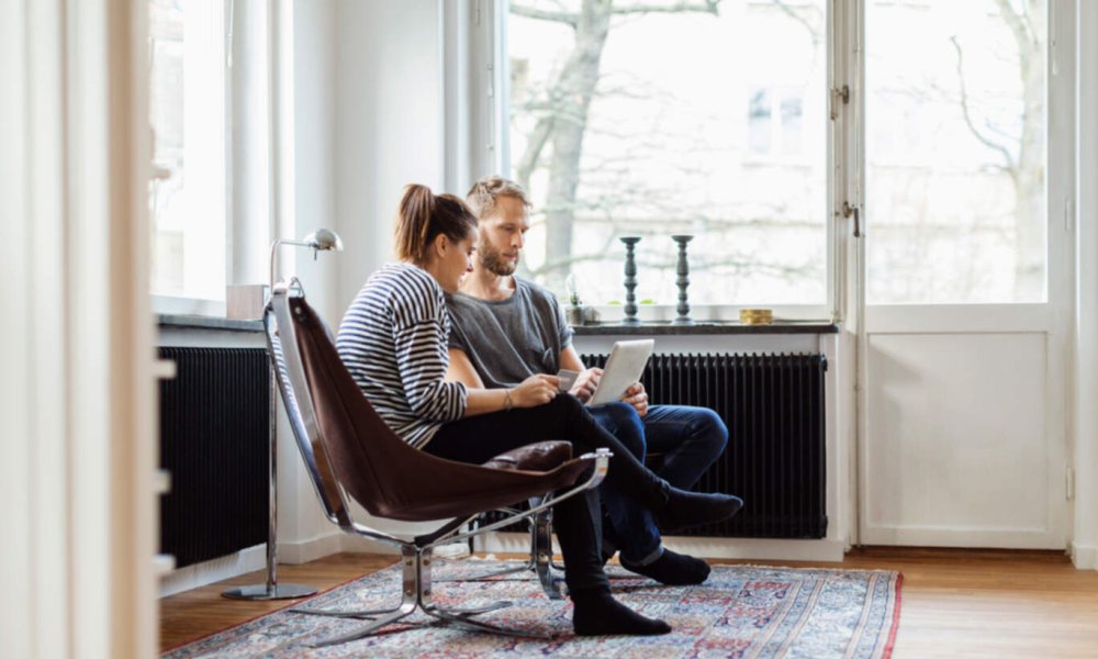 Illustrasjonsfoto: En kvinne og en mann sitter i en stue og ser inn i et nettbrett.