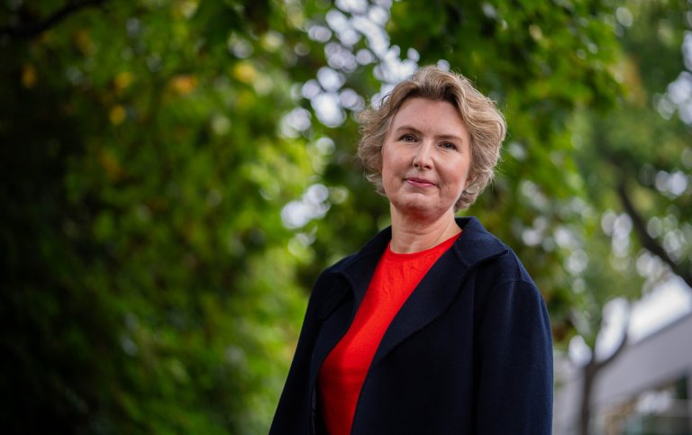 Hanne Iversen Rye i Storebrand utendørs med grønne trær i bakgrunnen.