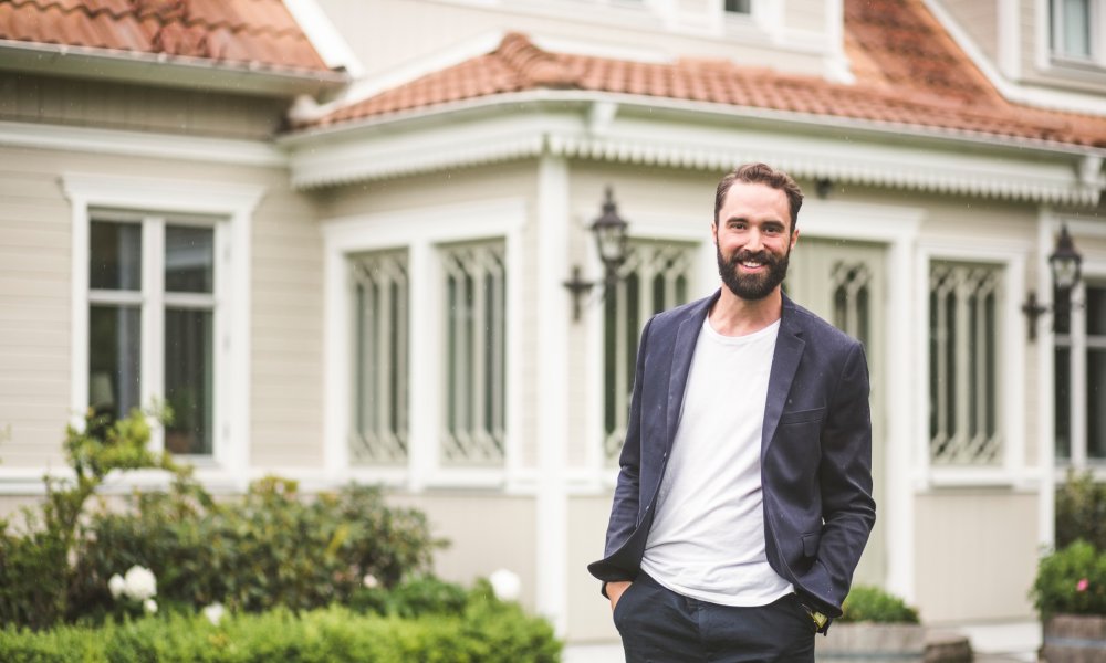 Illustrasjonsfoto: En mann med blazer står foran et stort hus.